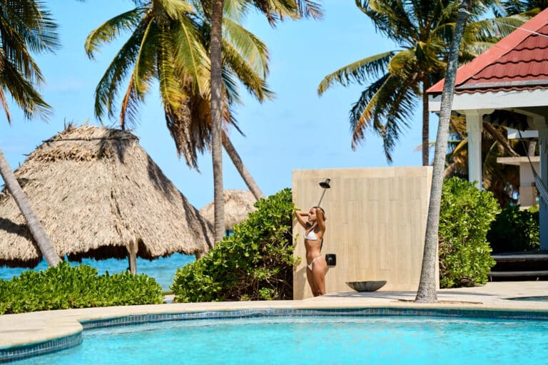 Guest rinsing off in the poolside shower at The Resort at Almond Beach, Hopkins Village, Stann Creek District, Southern Belize